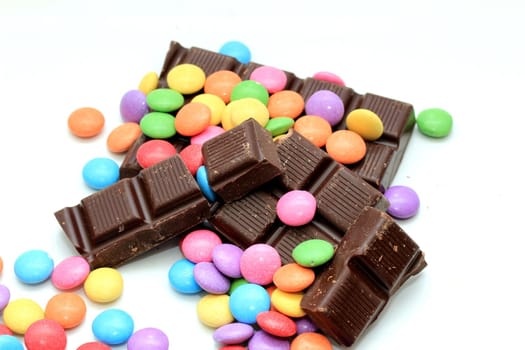 Chocolate filled candies in various bright colors and pieces of a chocolate bar