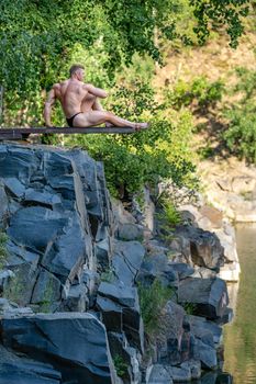 male bodybuilder on the rok in nature, fitness and healthy.