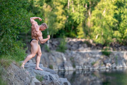 male bodybuilder by the water in nature.