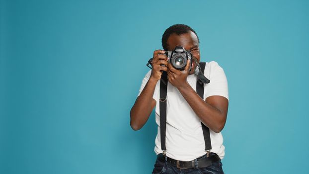 Portrait of male photographer taking pictures with professional camera, using photography equipment to capture creative photos. Focused man shooting with digital lens for production.