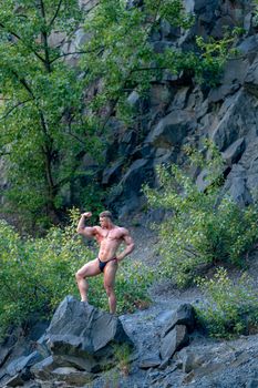 male bodybuilder on the rok in nature, fitness and healthy.