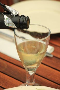 Man pouring white wine at a dinner table