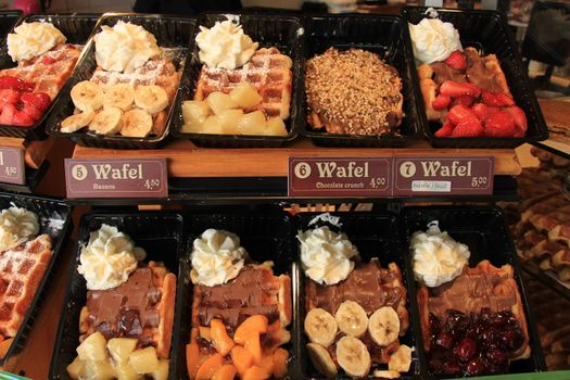 Fresh made Belgium waffles with various fruit toppings and cream (tags: product and price information in English and Dutch.