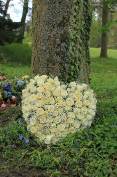 Heart shaped sympathy flowers  or funeral flowers near a tree