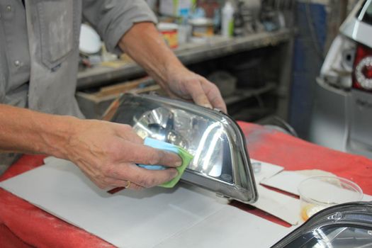 Man refurbishing a car headlight with clear coating