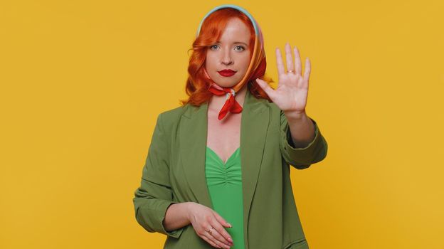 No stop. Serious woman say No, hold palm folded crossed hands in stop danger gesture, warning of finish, prohibited access, declining communication, body language. Redhead girl on yellow background