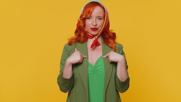I am the best, choose me. Redhead young woman feeling very proud pointing herself, looking self-confident, overjoyed by success. Adult ginger girl indoors studio shot isolated on yellow background