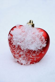 Red heart shaped ornament in fresh fallen snow