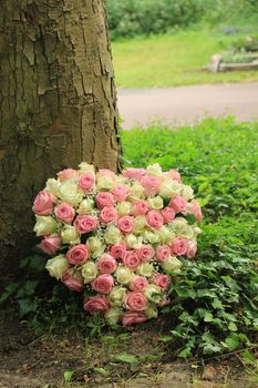 Heart shaped sympathy flowers near a tree at a cemetery