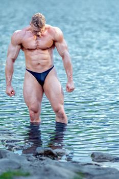 male bodybuilder in the water in nature.