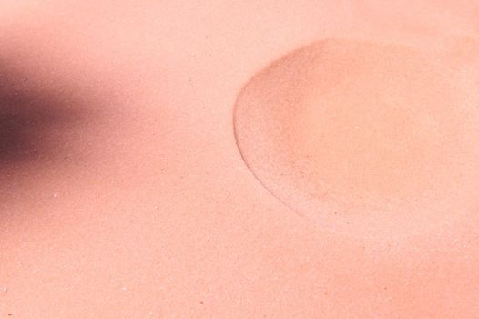The formed crater on pure pink sand. Sandy background. Copy space for promotional and advertising text. Minimalistic art design