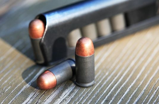 Handgun cartridges closeup on old wooden background