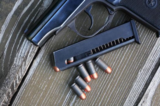 Handgun cartridges closeup on old wooden background near pistol