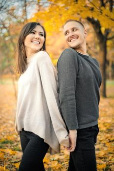 Young smiling couple having fun together on weekends in autumn park.