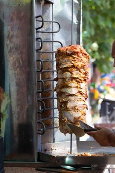 Chef cutting with doner knife Traditional Turkish Doner Kebab meat. Shawarma or gyros. Turkish, greek or middle eastern arab style chicken doner kebab food.