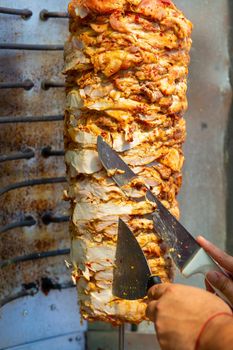 Chef cutting with doner knife Traditional Turkish Doner Kebab meat. Shawarma or gyros. Turkish, greek or middle eastern arab style chicken doner kebab food.