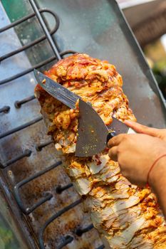 Chef cutting with doner knife Traditional Turkish Doner Kebab meat. Shawarma or gyros. Turkish, greek or middle eastern arab style chicken doner kebab food.