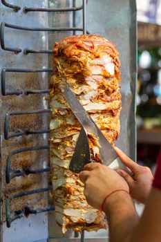 Chef cutting with doner knife Traditional Turkish Doner Kebab meat. Shawarma or gyros. Turkish, greek or middle eastern arab style chicken doner kebab food.