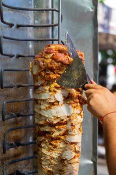 Chef cutting with doner knife Traditional Turkish Doner Kebab meat. Shawarma or gyros. Turkish, greek or middle eastern arab style chicken doner kebab food.