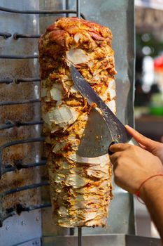 Chef cutting with doner knife Traditional Turkish Doner Kebab meat. Shawarma or gyros. Turkish, greek or middle eastern arab style chicken doner kebab food.