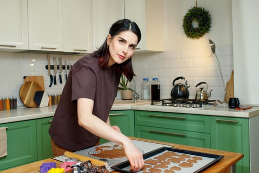 Young brunette woman cooking homemade dessert in home kitchen, look at camera.