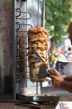 Chef cutting with doner knife Traditional Turkish Doner Kebab meat. Shawarma or gyros. Turkish, greek or middle eastern arab style chicken doner kebab food.