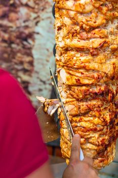 Chef cutting with doner knife Traditional Turkish Doner Kebab meat. Shawarma or gyros. Turkish, greek or middle eastern arab style chicken doner kebab food.