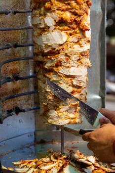 Chef cutting with doner knife Traditional Turkish Doner Kebab meat. Shawarma or gyros. Turkish, greek or middle eastern arab style chicken doner kebab food.