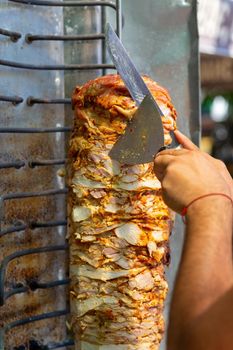 Chef cutting with doner knife Traditional Turkish Doner Kebab meat. Shawarma or gyros. Turkish, greek or middle eastern arab style chicken doner kebab food.