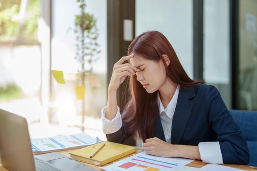 Portrait of an Asian businesswoman showing a headache from depression.