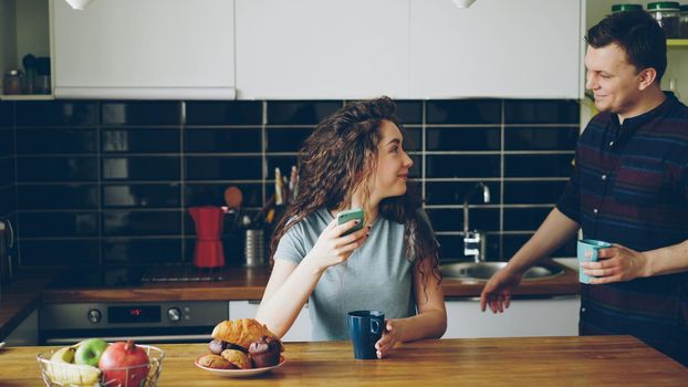 young happy positive caucasian couple in love meeting in the morning in modern kitchen at table to have breakfast together