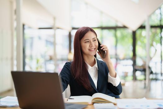 Asian businesswoman using the phone to contact a business partner.