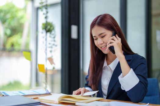 Asian businesswoman using the phone to contact a business partner.