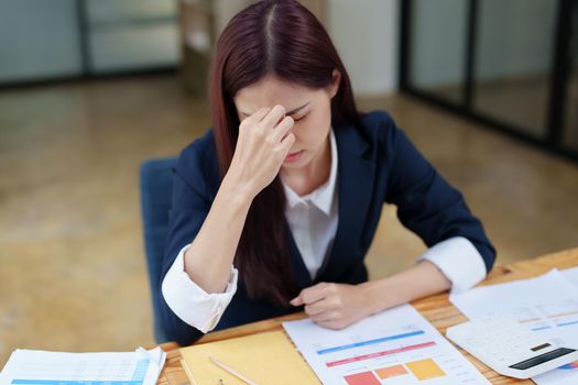 Portrait of an Asian businesswoman showing a headache from depression.