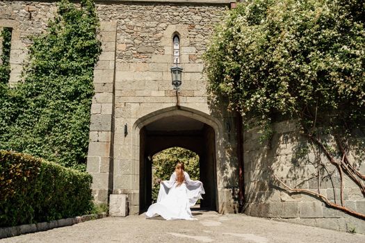 a beautiful woman in a white dress walks through a beautiful palace on a sunny day.