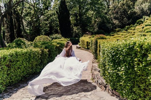 a beautiful woman with long brown hair runs along a path along beautiful bushes in the park