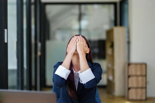 Portrait of an Asian businesswoman showing a headache from depression.