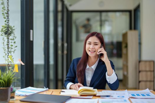 Asian businesswoman using the phone to contact a business partner.