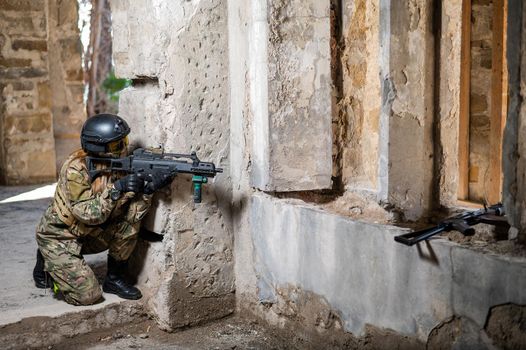 A woman in an army uniform shoots a firearm in an abandoned building