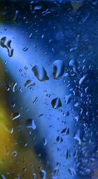 Macrophotography.Water drops on a glass surface with blue-yellow illumination.Texture or background