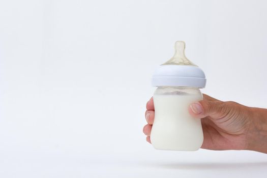 Isolated baby bottle feeding full of milk in cropped woman hand on white background with copy space