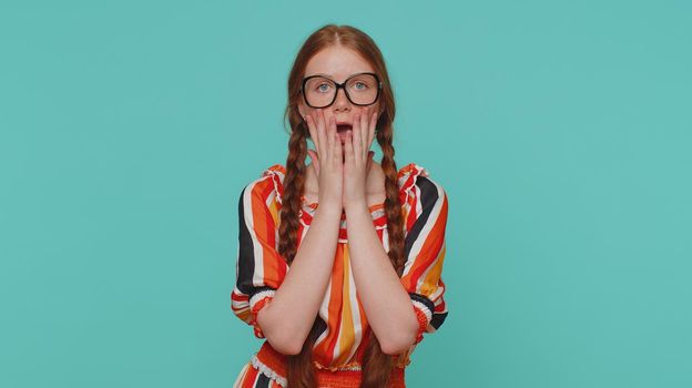 Stressed depressed redhead girl 16 years old expresses her fear and waves her hands away from danger, waving no. Scared fearful ginger teenager child isolated alone on blue studio wall background
