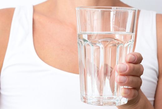 Cropped caucasian middle aged woman holding glass of pure water on white background