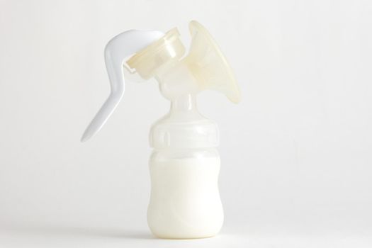 Isolated baby manual breast pump full of milk on white background