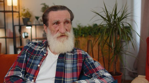 Close-up of sad sick senior old grandfather man at home looks pensive thinks over life concerns or illness, suffers from unfair situation. Problem, break up, depressed feeling bad annoyed, burnout