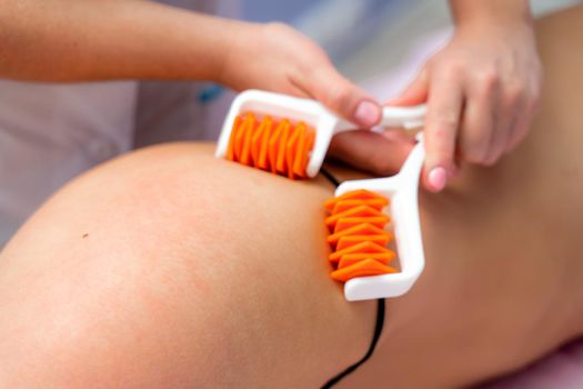 The masseur makes anti-cellulite massage using a roller massager. Physiotherapy and rehabilitation treatment