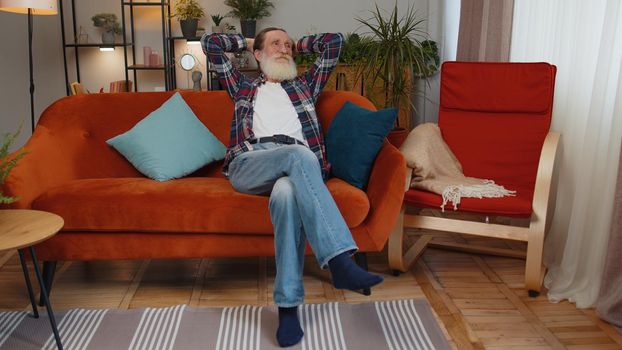 Portrait of happy calm senior old grandfather man pensioner smiling friendly, glad expression looking away dreaming resting, relaxation feel satisfied concept good news sitting on sofa at home room