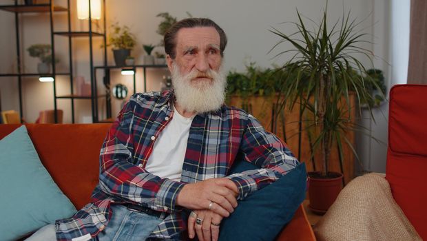 Portrait of sad sick senior old grandfather man at home looks pensive thinks over life concerns or illness, suffers from unfair situation. Problem, break up, depressed feeling bad annoyed, burnout