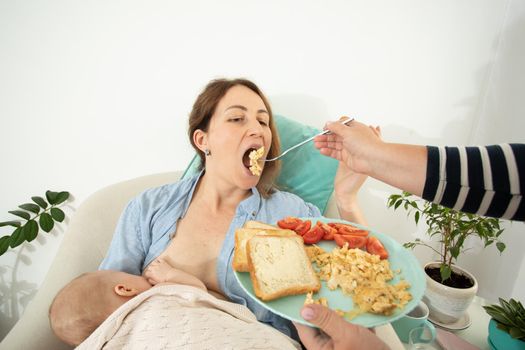 Elder woman helps to eat for new mother when she breastfeeds her baby. Motherhood support