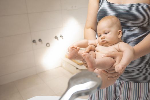 Mother washes her baby after stool at the bath